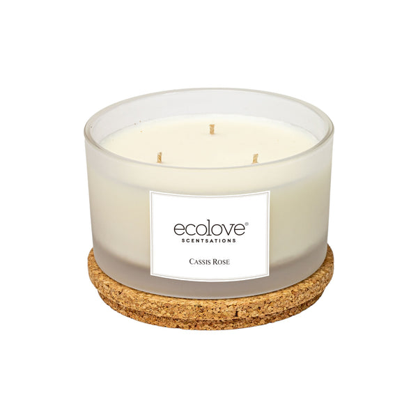 Vela perfumada com três pavios, em recipiente de vidro fosco, com cera branca, e tampa de cortiça. Design simples e elegante. Aroma de rosa e groselha. A etiqueta retangular, de papel branco, tem escrito o nome Ecolove e o aroma: “Cassis Rose”, em letra preta.